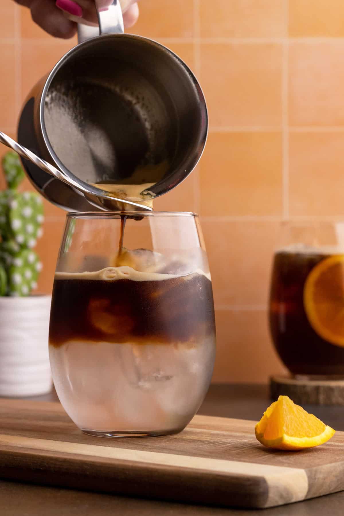 Pouring espresso into a glass with tonic water.