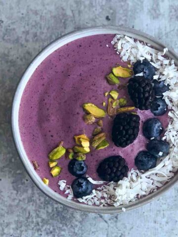Blackberry smoothie bowl with toppings overhead.