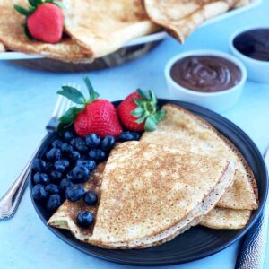 Crepes with blueberries and strawberries on a plate.