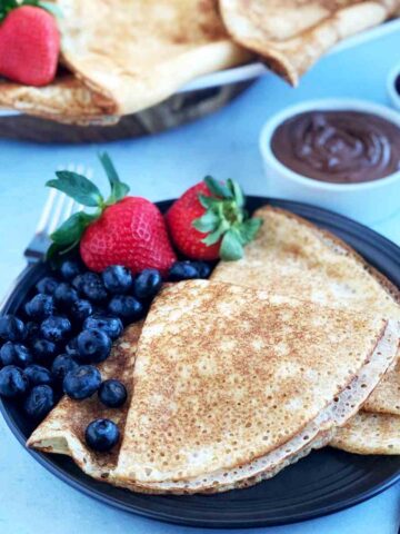 Crepes with blueberries and strawberries on a plate.
