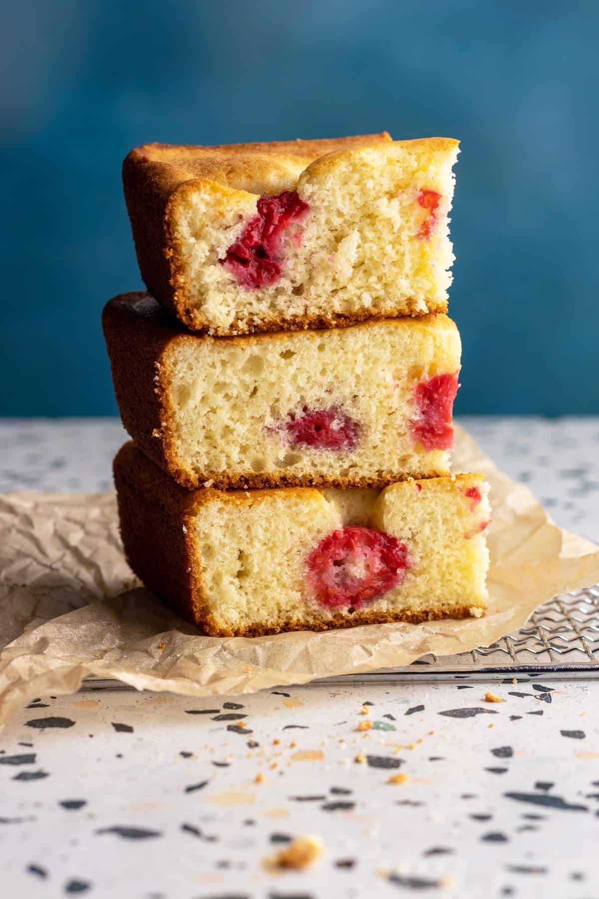 Stacked raspberry cake bars on parchment paper.