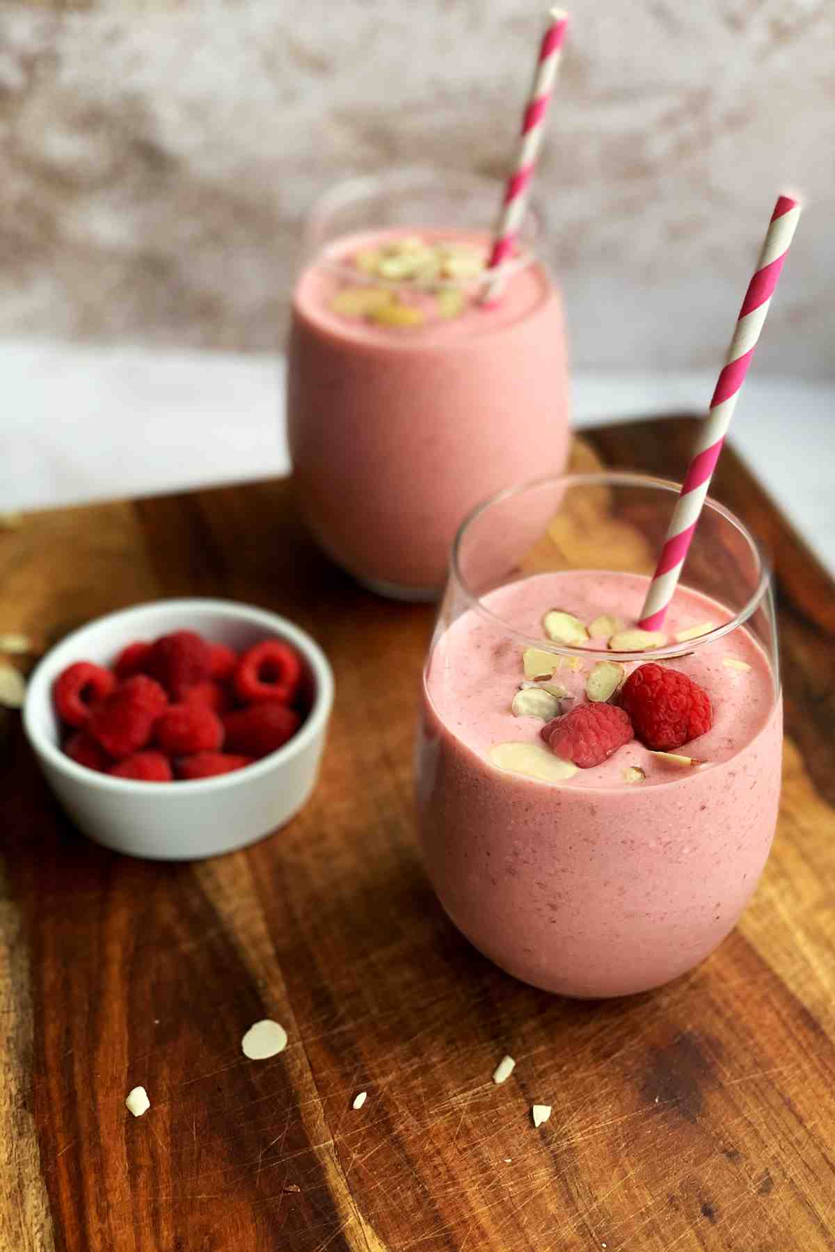 Strawberry banana raspberry smoothie in a glass with toppings.