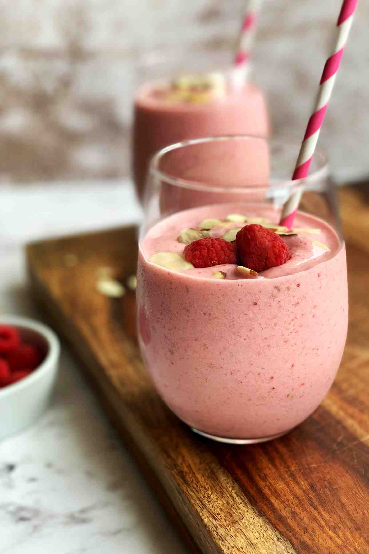 Strawberry banana raspberry smoothie in a glass on wooden board.