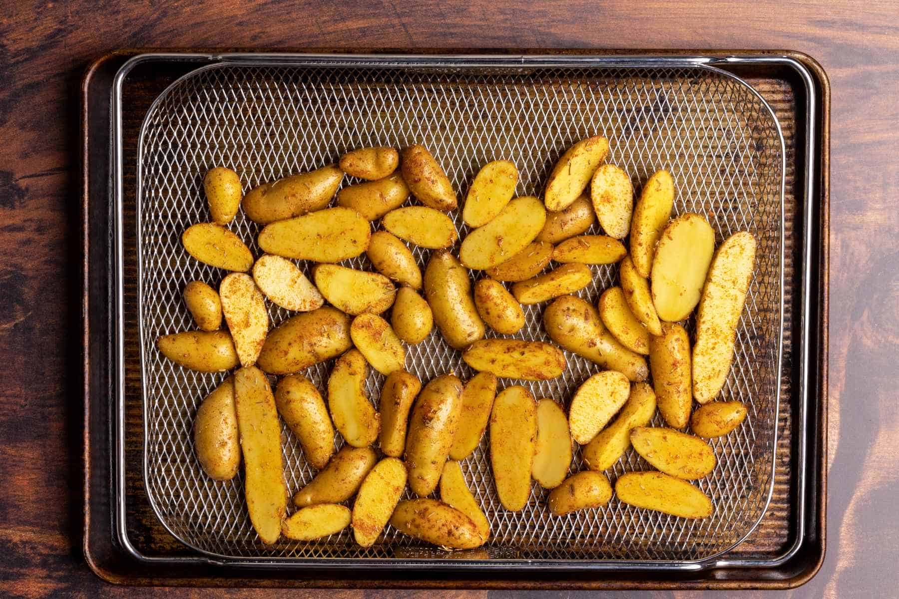 Seasoned fingerling potatoes in air fryer basket.