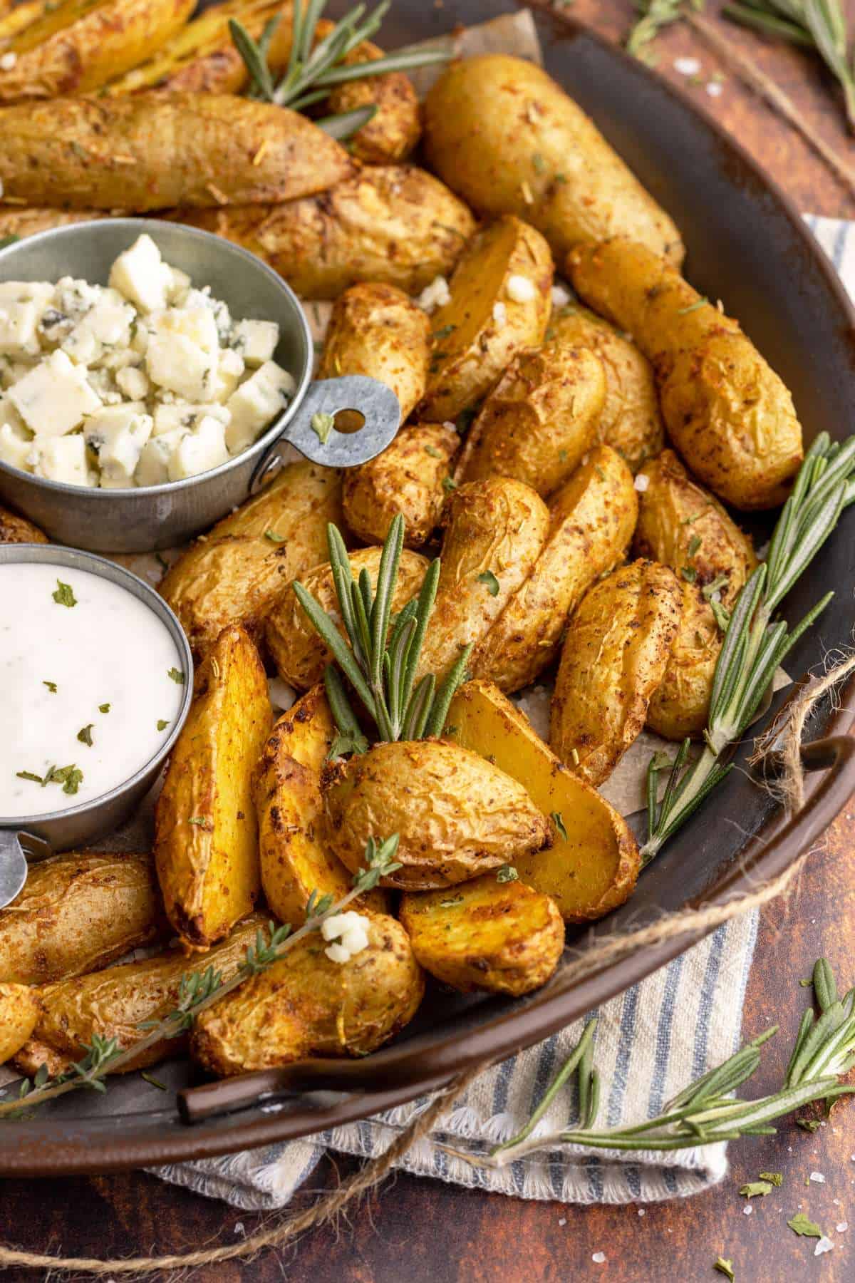Air fryer fingerling potatoes with rosemary in metal tray.