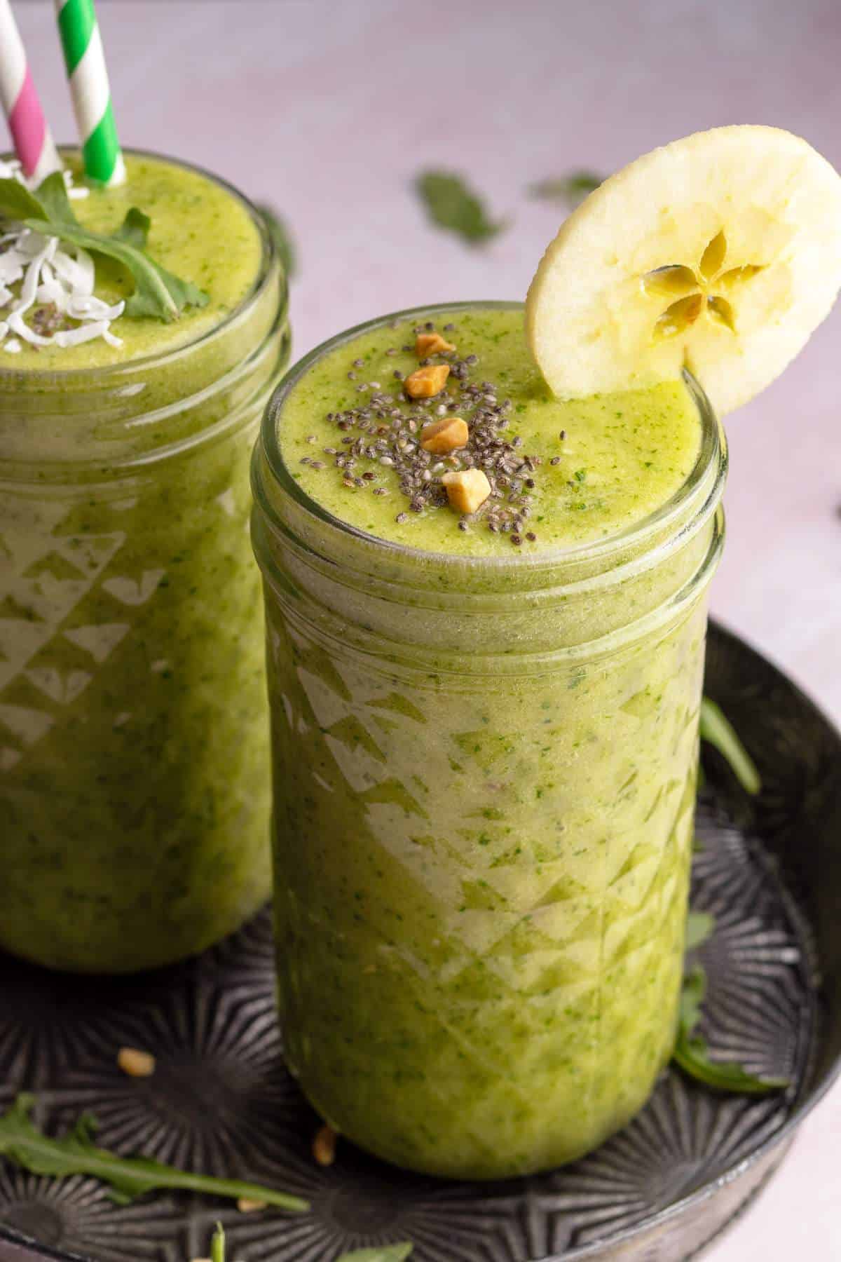 Arugula banana smoothie in jars on a metal serving tray.