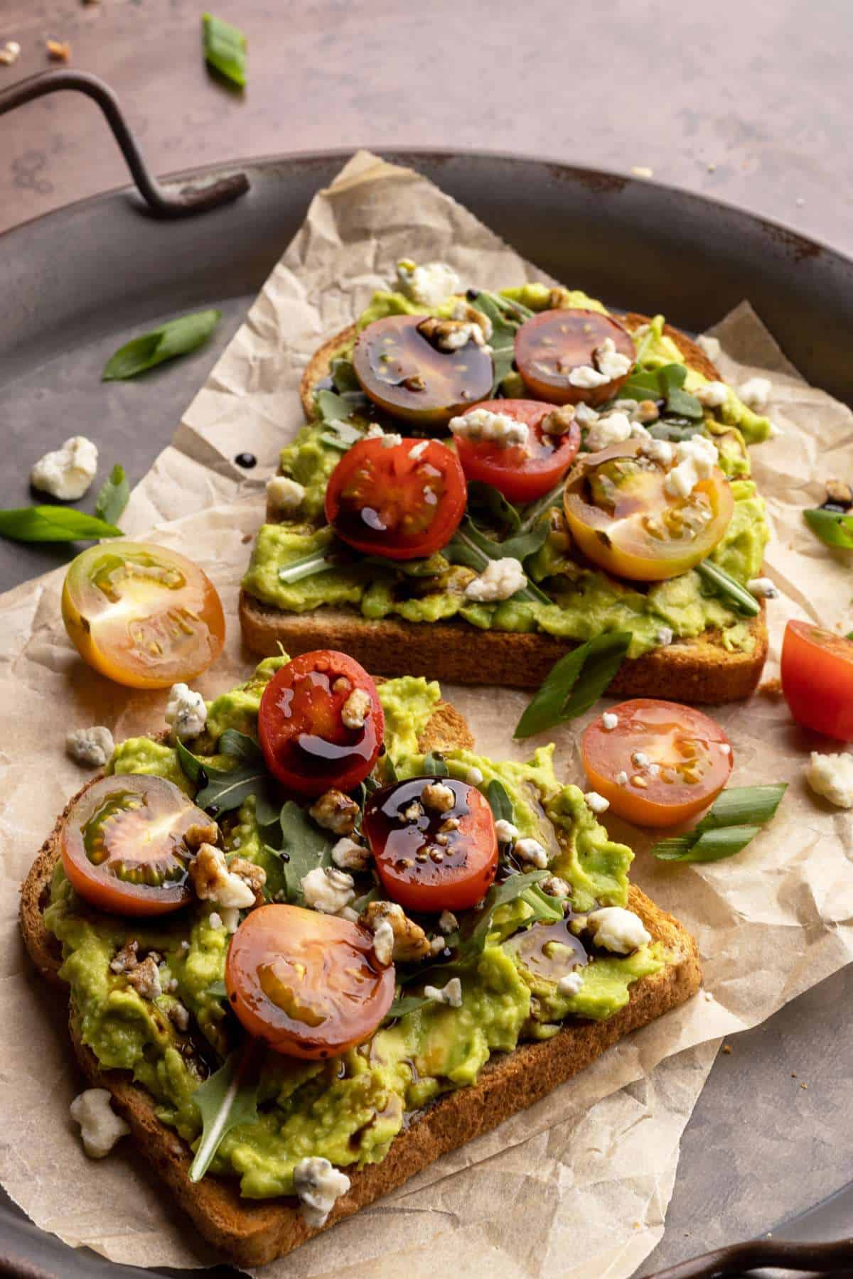 Avocado toast on a tray with cherry tomatoes and balsamic glaze.