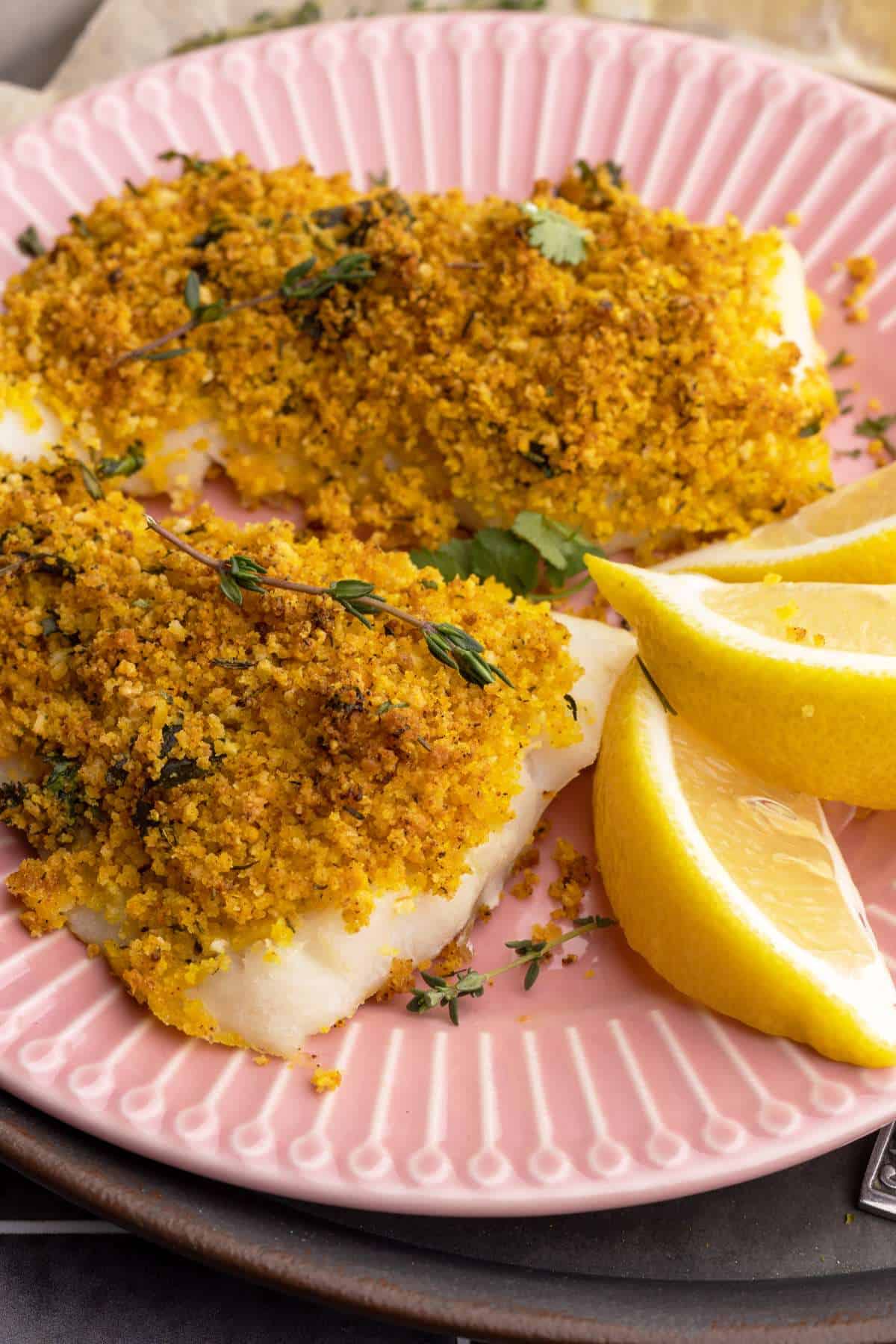 Baked cod with panko on plate closeup.