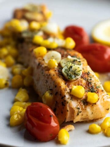 Baked salmon with veggies on a plate.