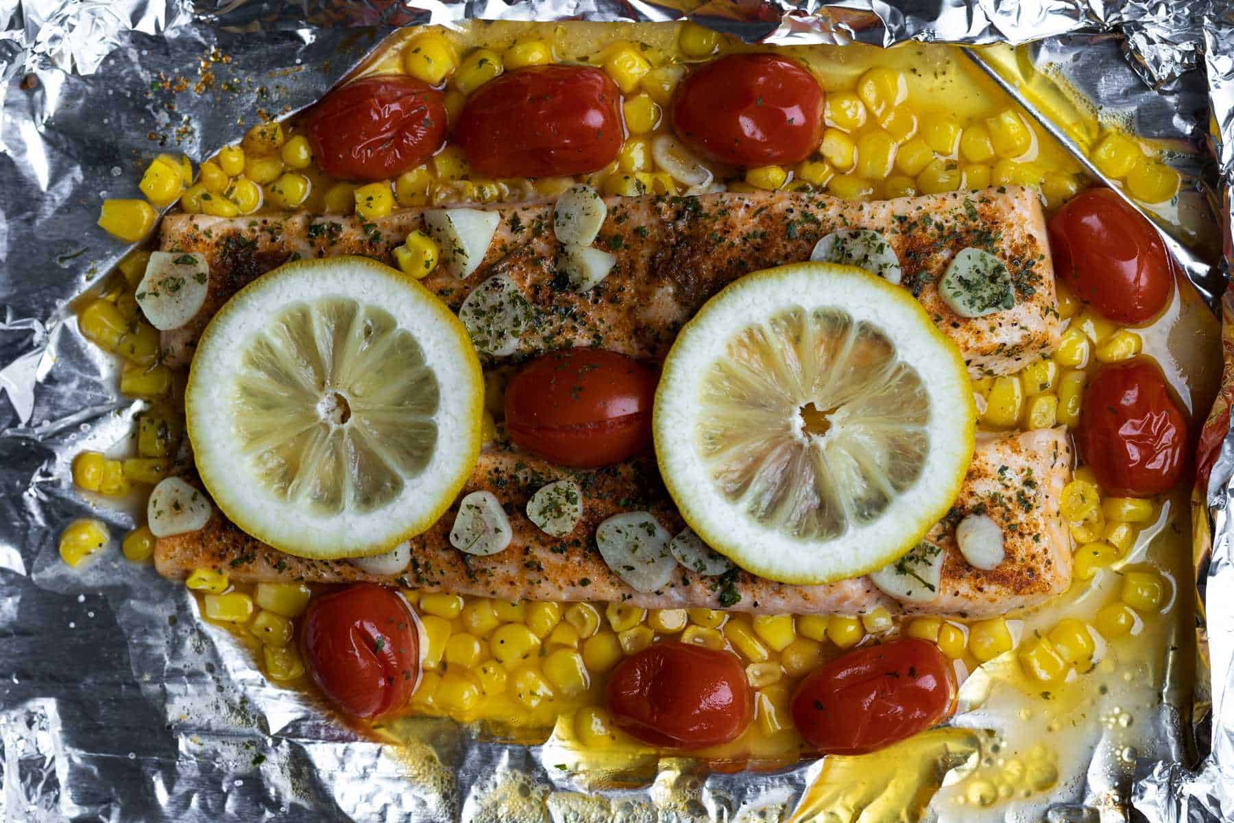Baked salmon with corn and tomatoes in foil.