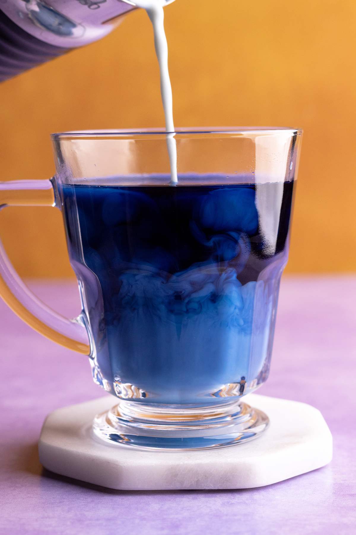 Butterfly pea flower latte pouring into the mug.