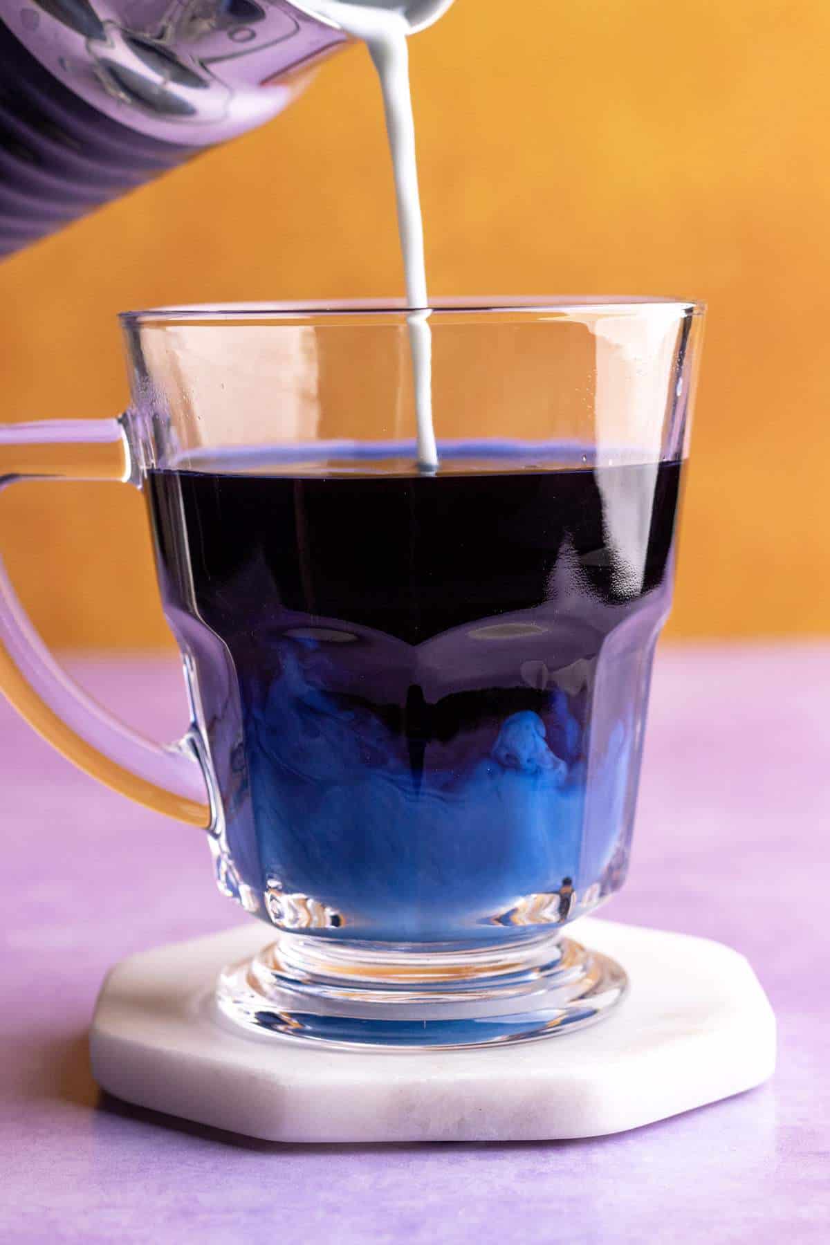 Butterfly pea latte pouring into the mug.