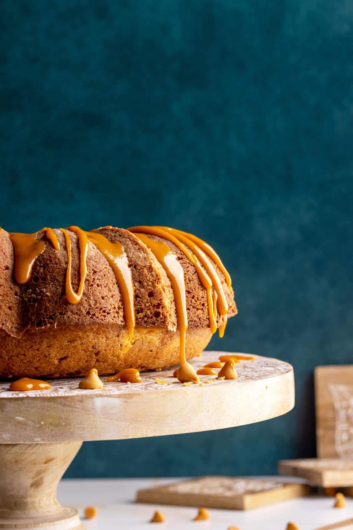 Butterscotch rum cake with a glaze on a cake stand head-on shot.