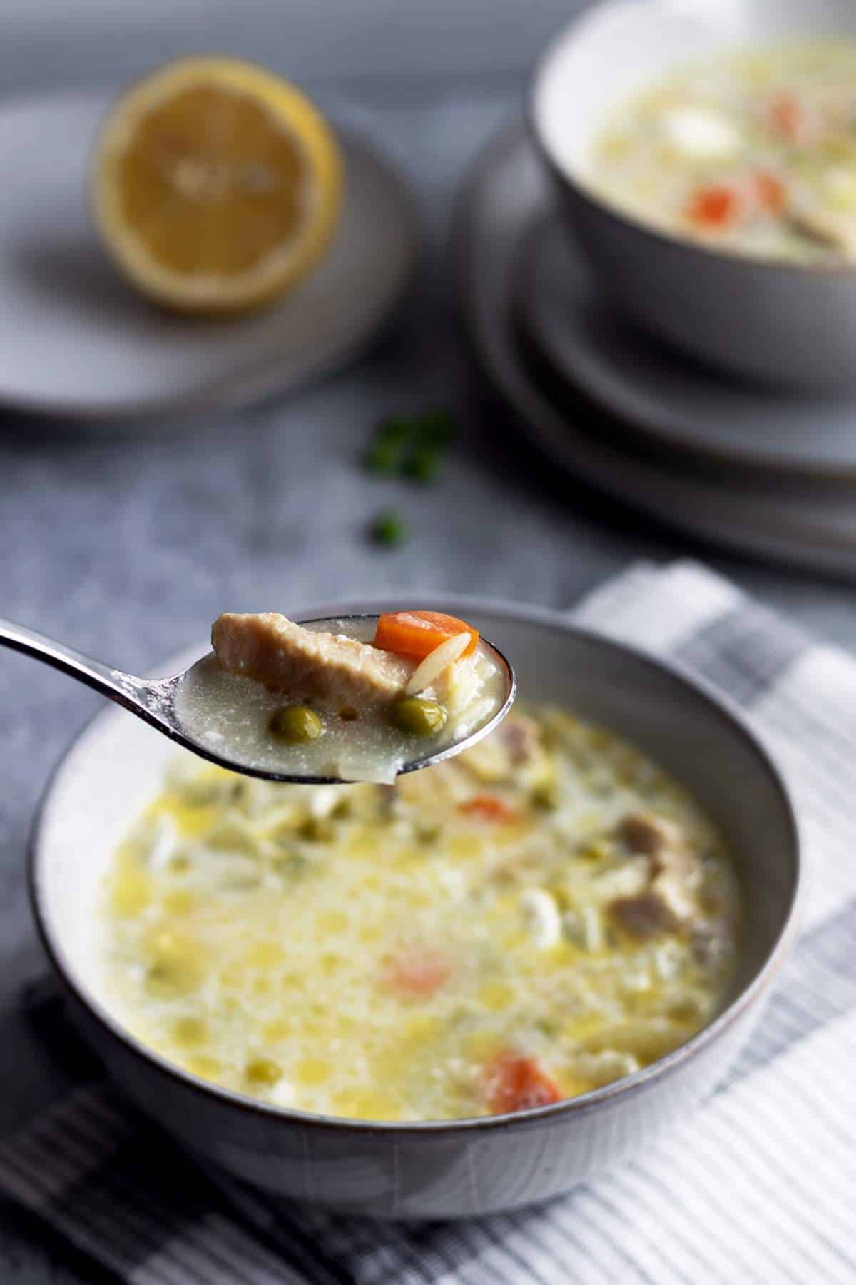 Chicken orzo soup in a spoon closeup shot.