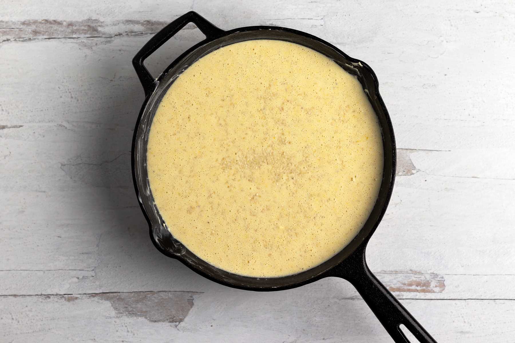 Cornbread ready to bake in a cast iron skillet.