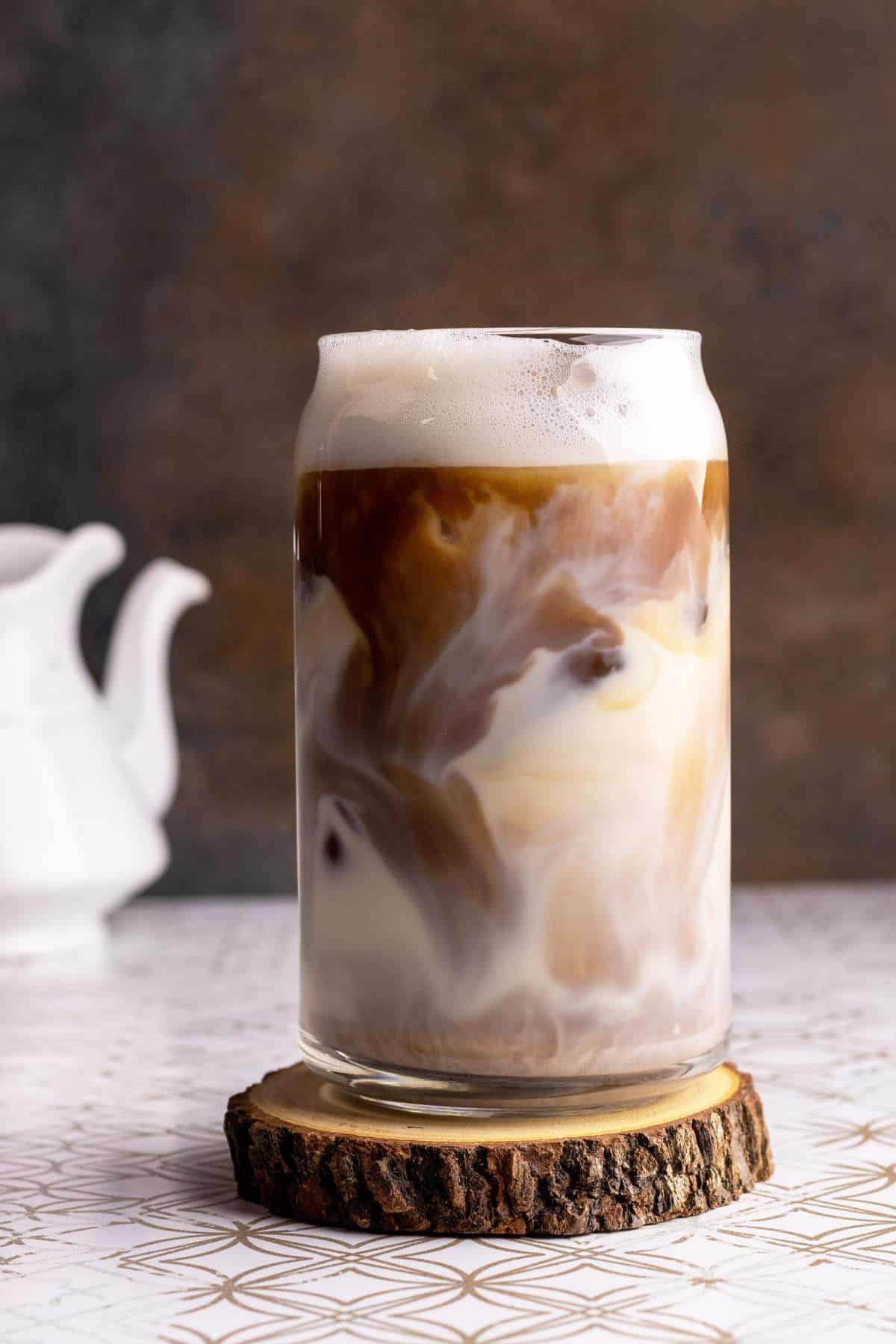 Espresso swirls in a glass with oat milk.