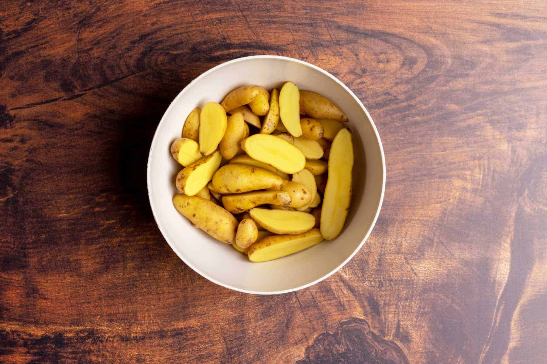 Fingerling potatoes cut lengthwise in a bowl.
