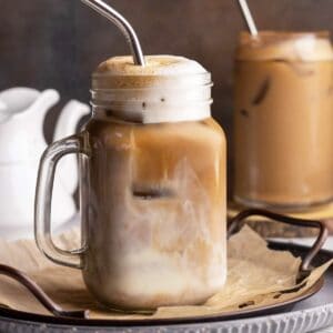 Frothy iced oat milk latte in a jar closeup shot.