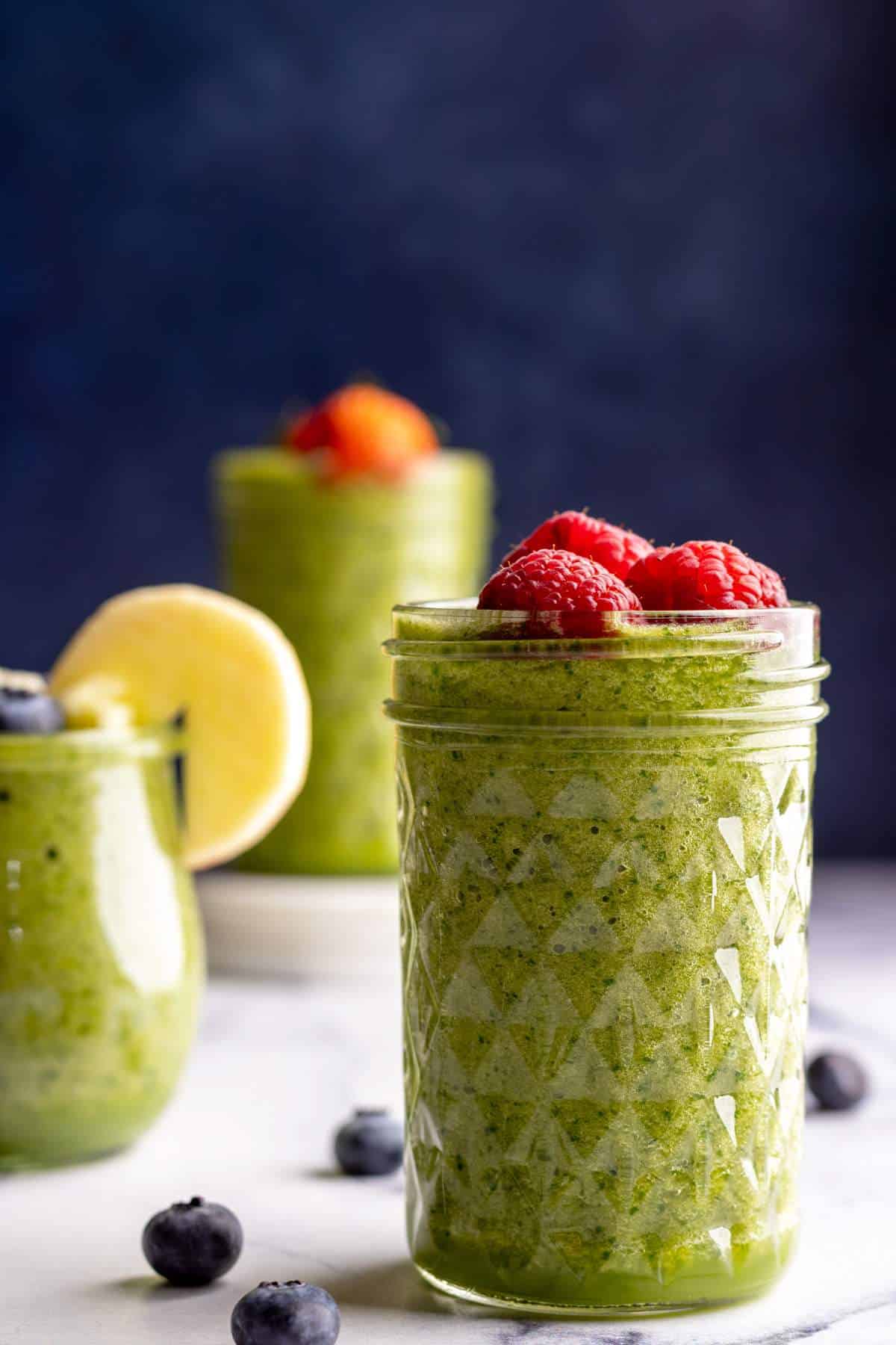 Green smoothie in a jar with raspberries on top closeup shot.