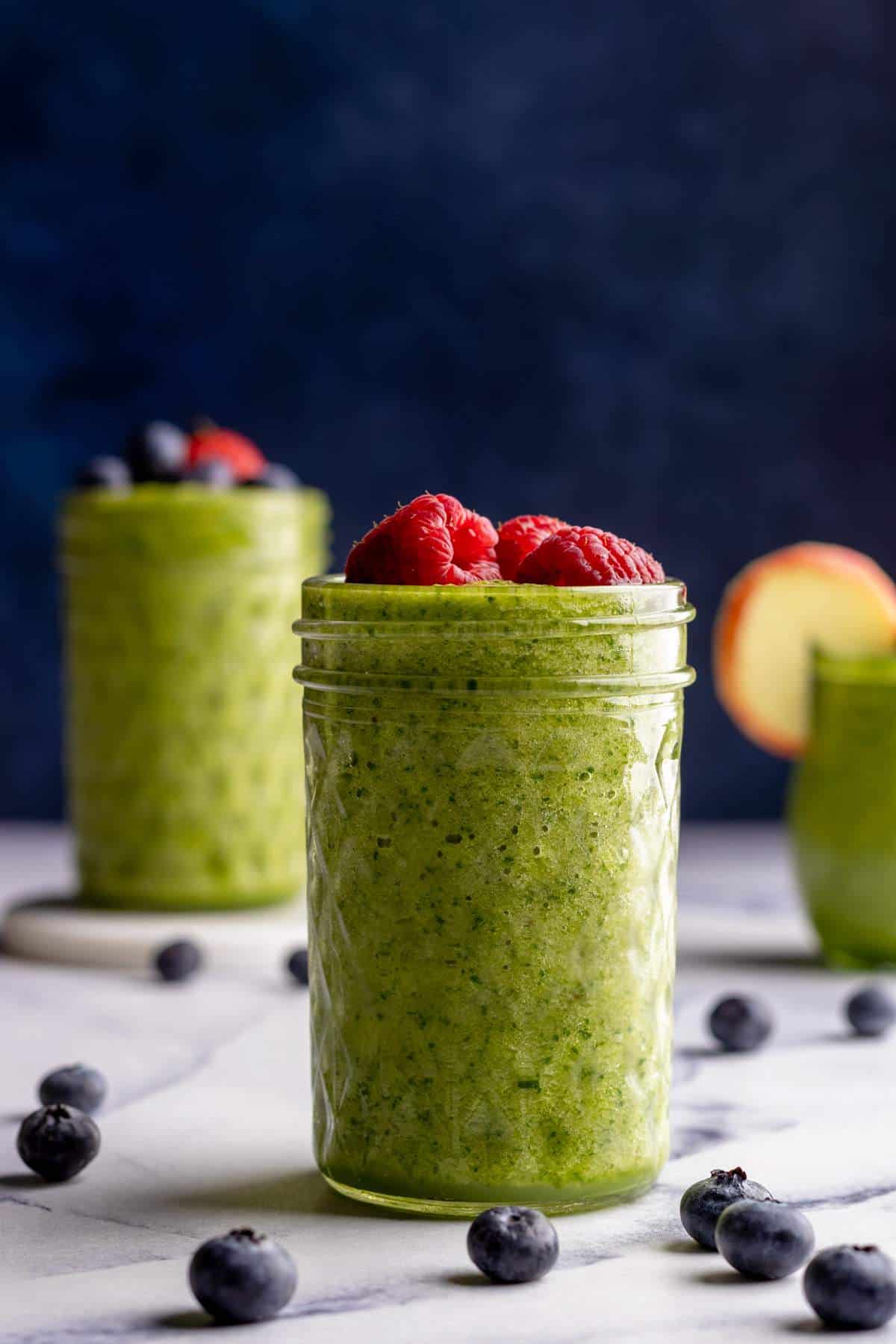 Green smoothie in jars with fruit toppings.