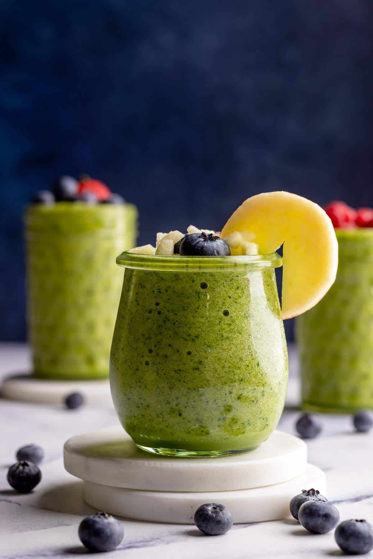 Green smoothie in a small jar with a sliced apple topping.