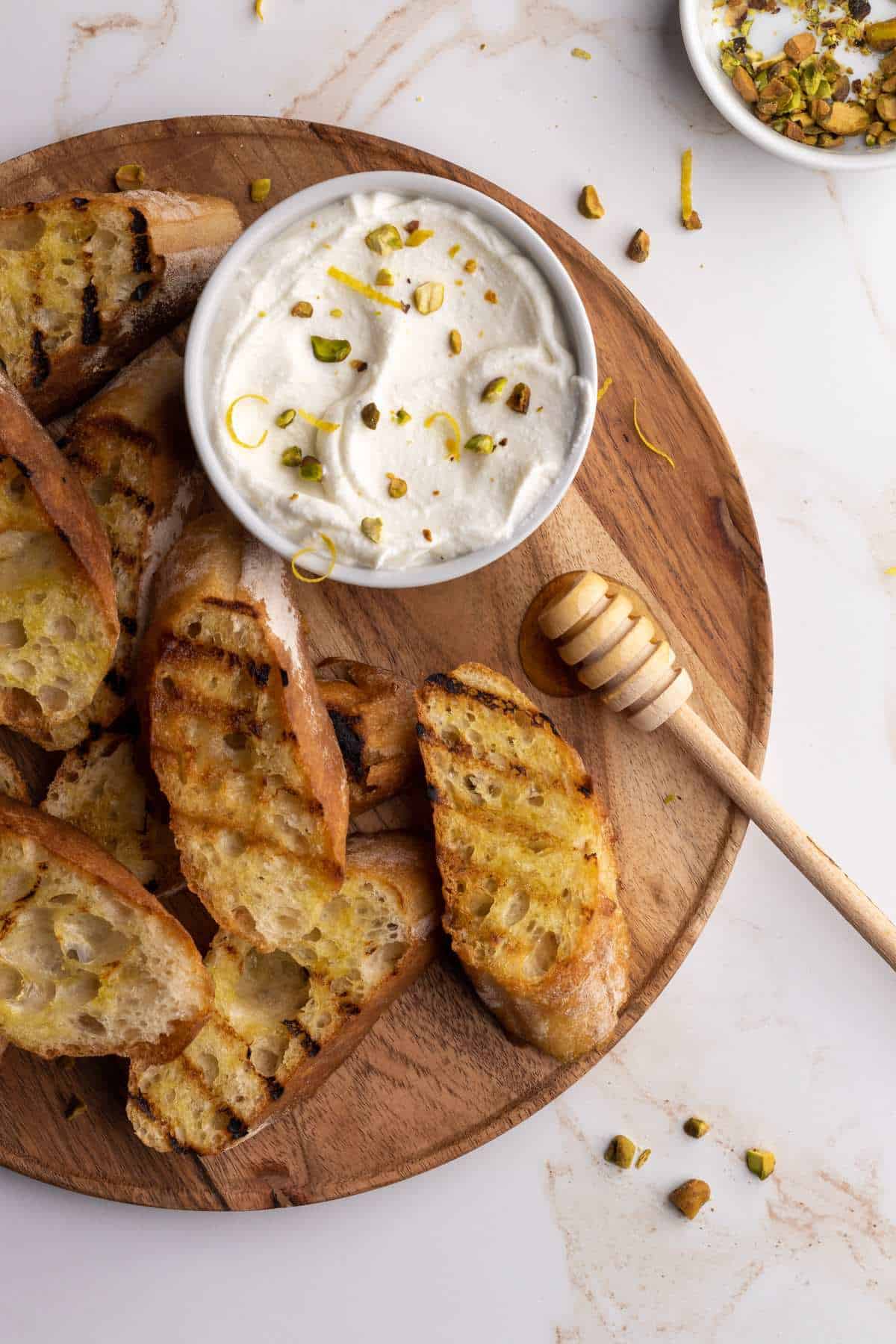 Grilled baguette with whipped ricotta on board.