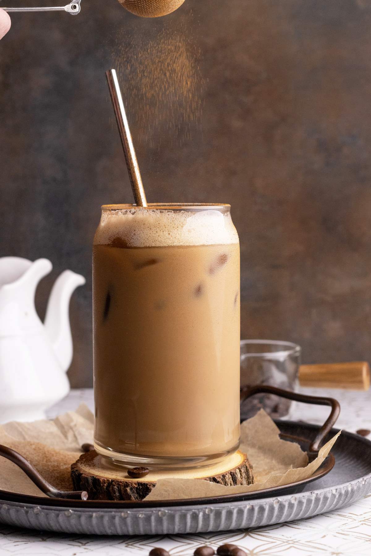 Oat milk latte in tall glass with cinnamon dust.