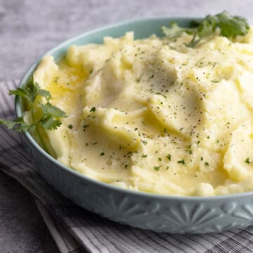 Mashed potatoes in a bowl with dry parsley sprinkled on top.