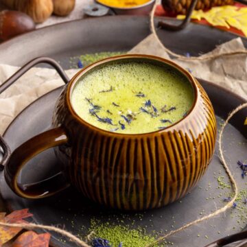 Matcha turmeric latte in a mug with dry edible flowers.
