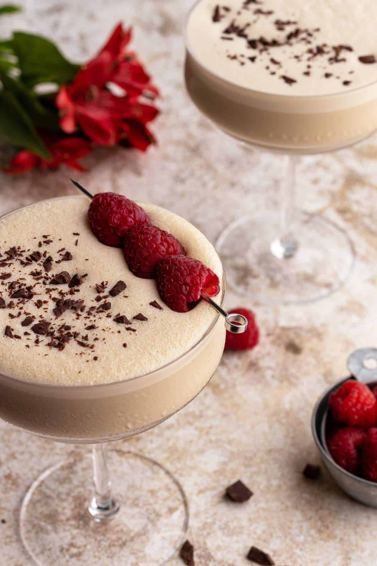 Raspberry chocolate martini in a glass with shaved chocolate pieces.