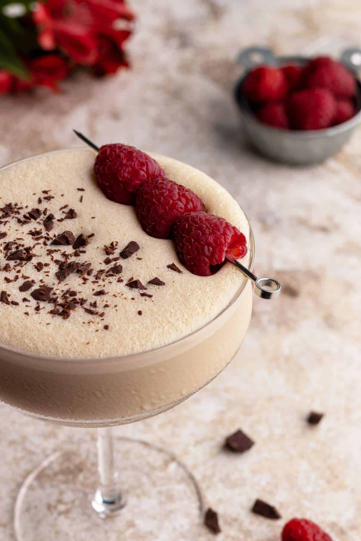 Raspberry chocolate martini in a glass with garnishes.