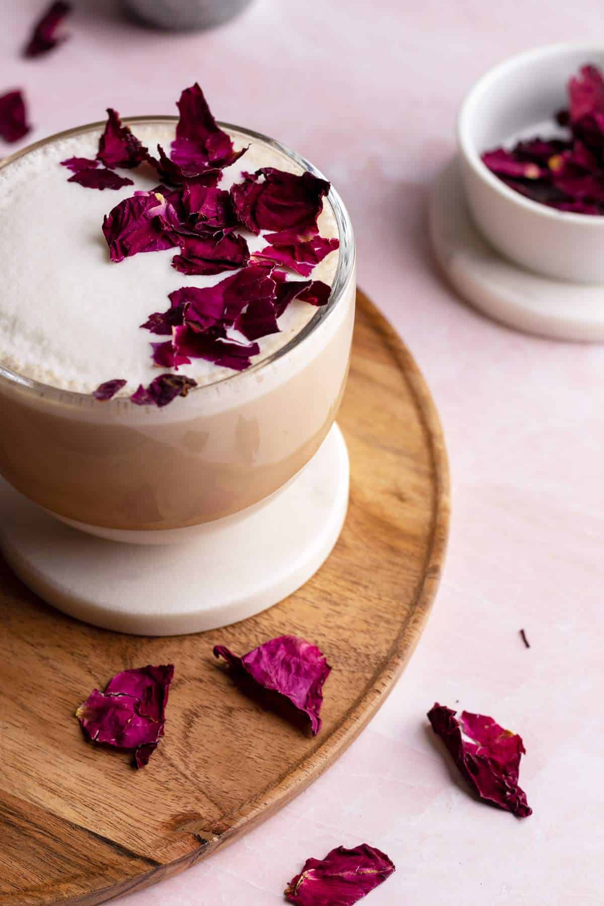 Rose chai latte in a cup with dry rose petals on top.