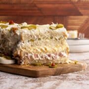 Savory sandwich cake on a wooden board head-on shot.