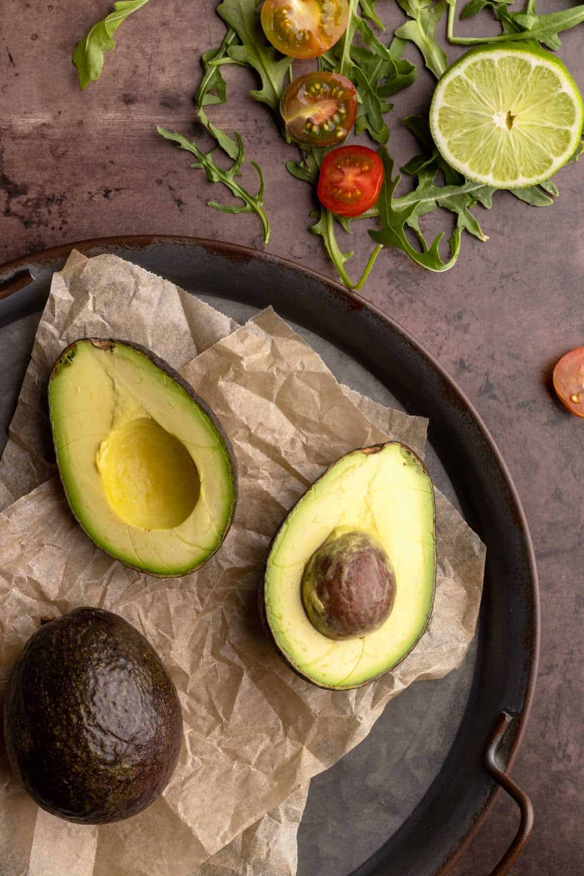 Sliced avocado in a tray with parchment paper.