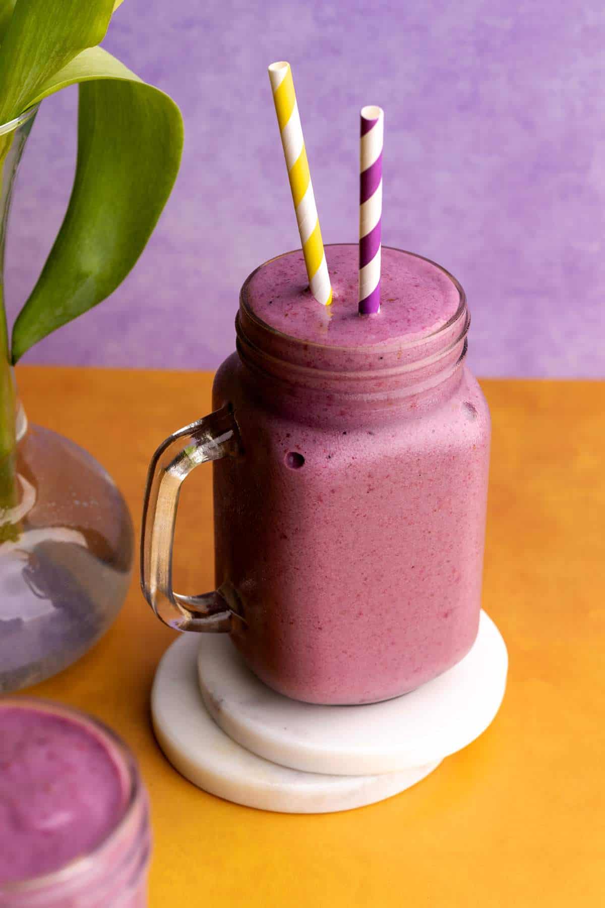 Blackberry and banana smoothie in a jar on a coaster.