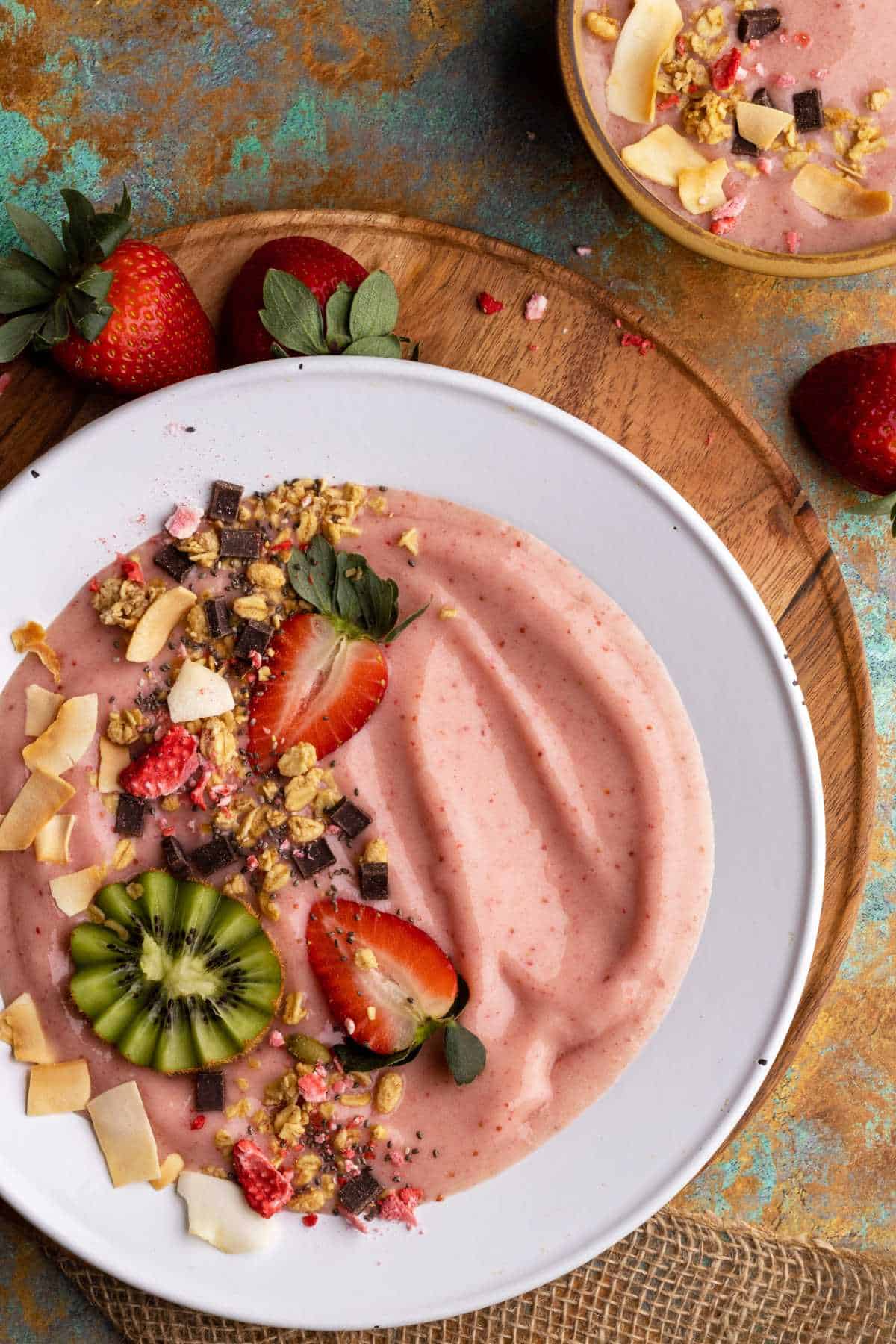 Strawberry smoothie bowl with fresh fruit and other toppings overhead.