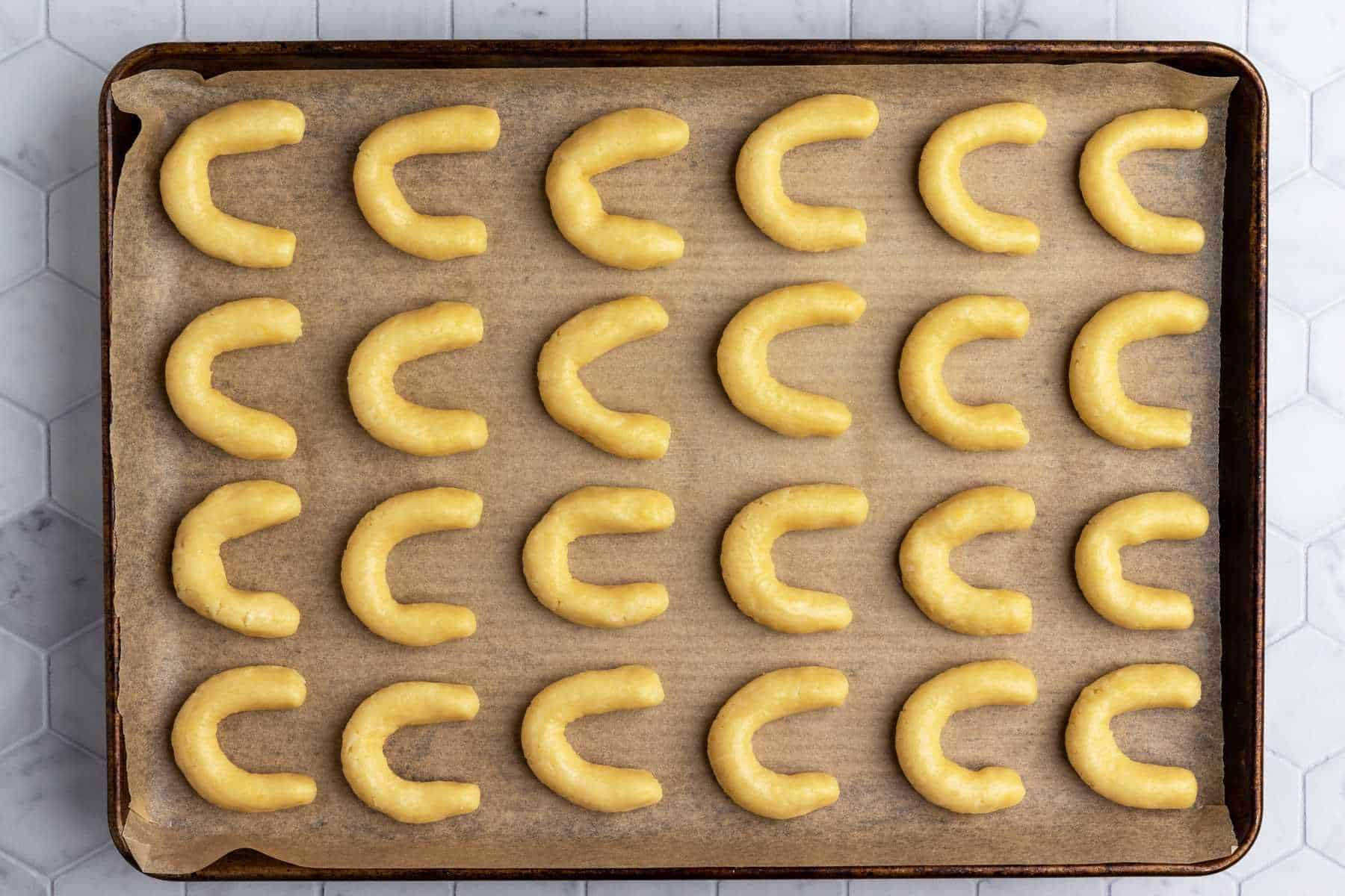 Vanilla crescent cookies on parchment-lined baking sheet.