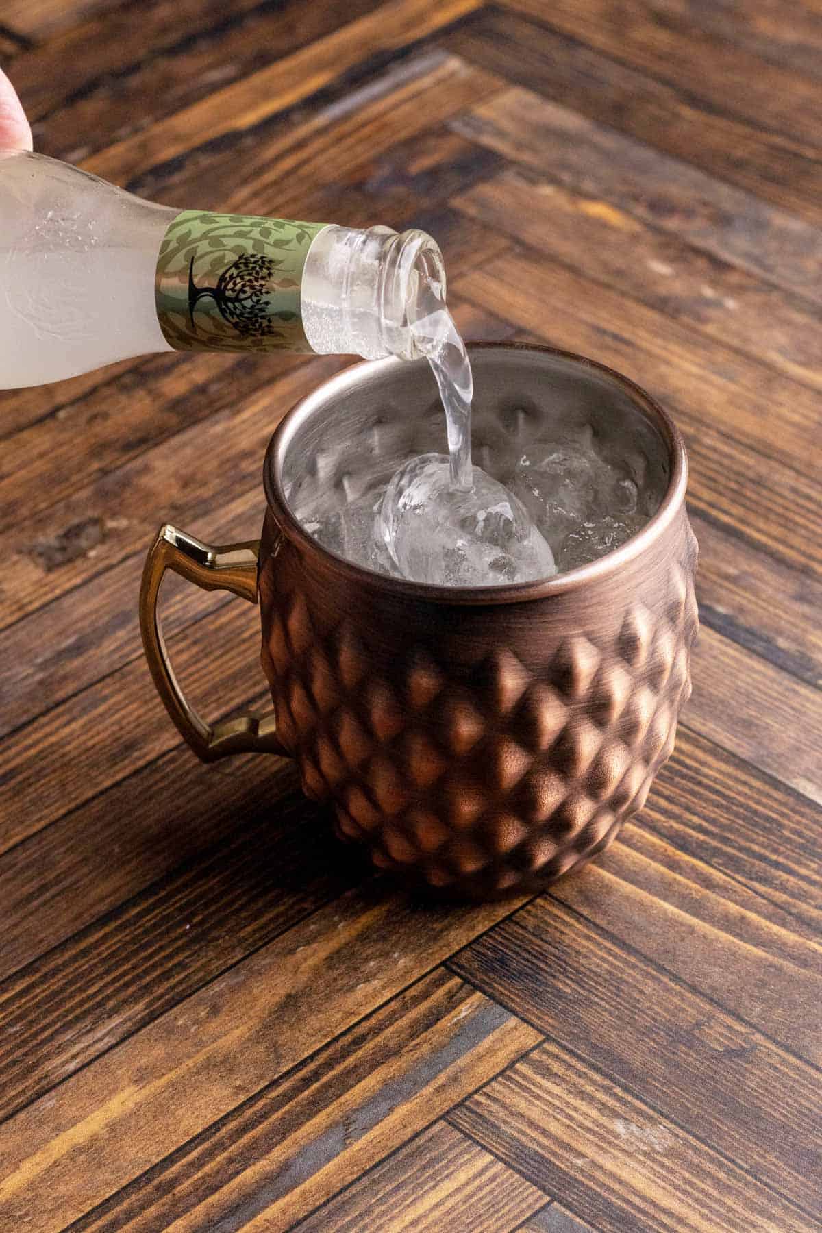 Adding ginger beer to a copper mug.