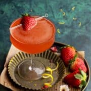 Strawberry martini on a metal tray with garnishes.