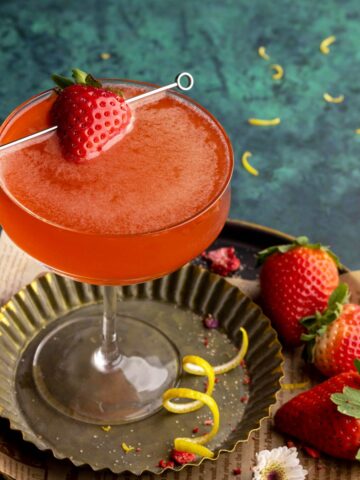 Strawberry martini on a metal tray with garnishes.