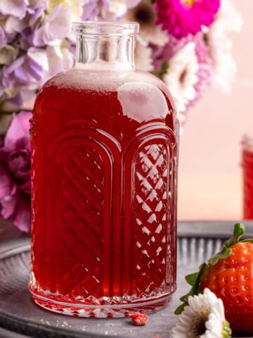 Strawberry simple syrup in syrup dispenser.