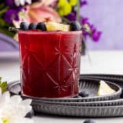 Blueberry gin cocktail with fruit and flowers on the tray.