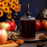 Apple simple syrup in a dispenser on a plate.