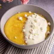 Serbian polenta in a bowl with sour cream and crumbled feta.