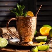 Rum Moscow mule in a copper mug surrounded with lime wedges.