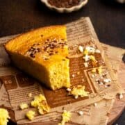 Cornbread piece on parchment paper with crumbs.