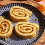 Sliced apricot jam swiss roll on a plate.